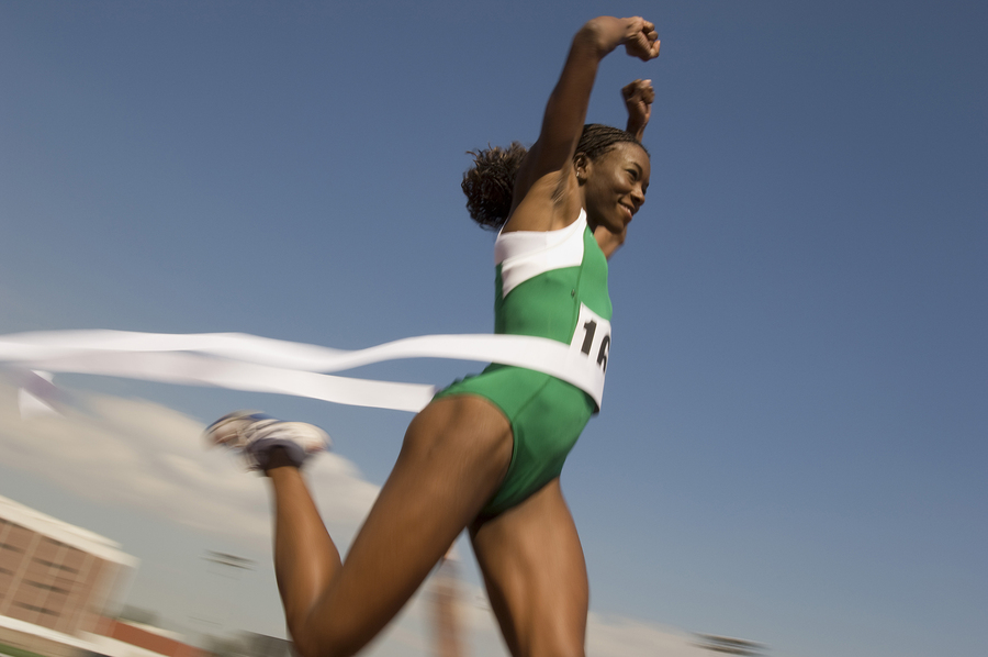 African American female athlete crossing finish line in race