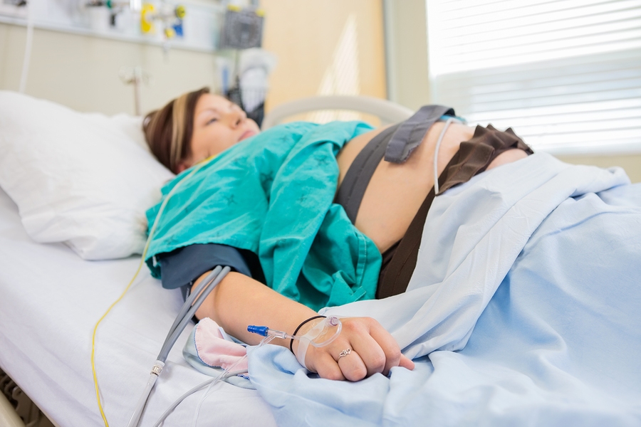 Birthing woman in hospital with IV in arm and epidural anesthesi